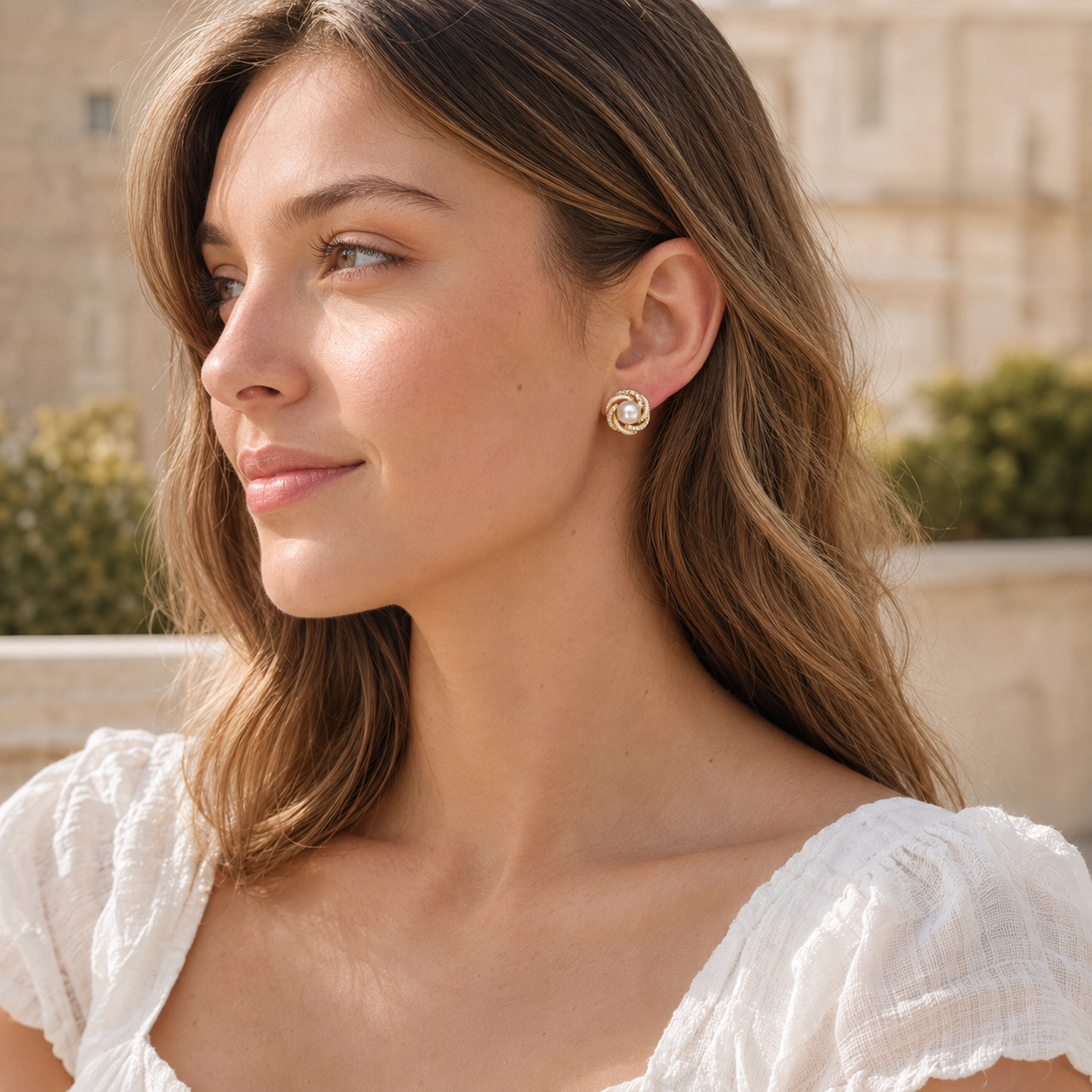 Model wearing gold pearl stud earrings outdoors