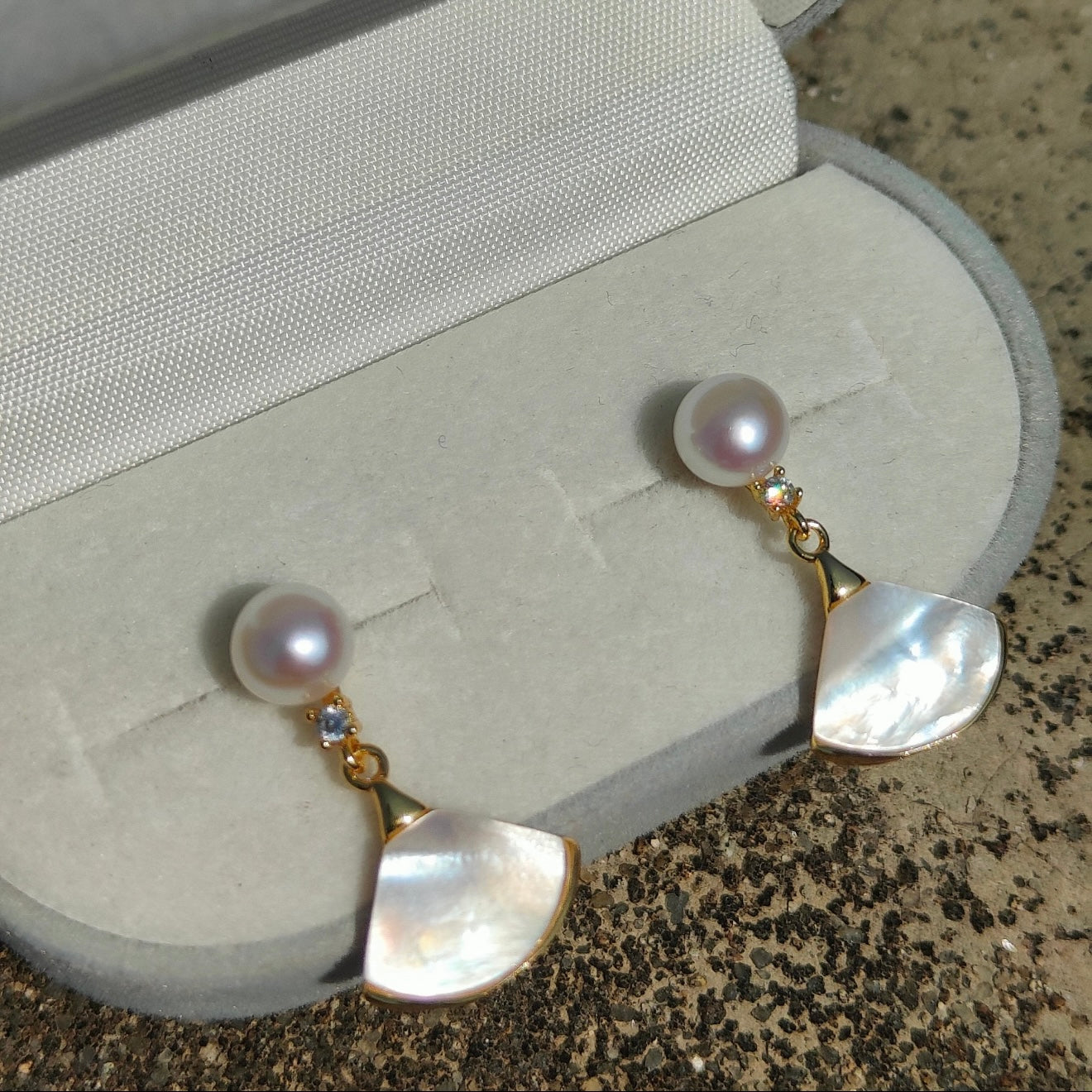 Pearl and mother-of-pearl fan earrings displayed in a jewellery box