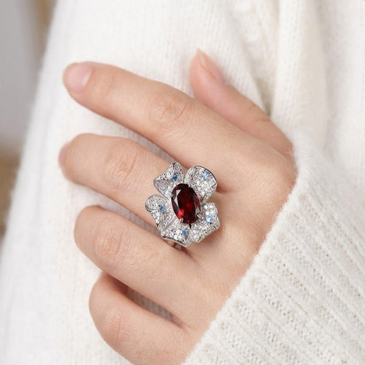 Elegant garnet flower ring in white gold with pavé stones worn on hand in soft indoor daylight