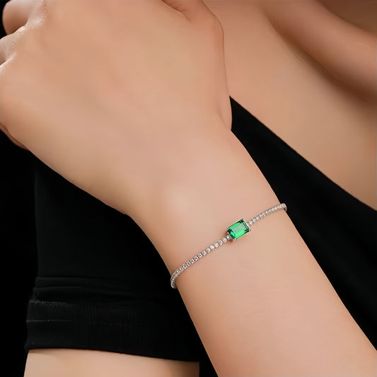 Model wearing emerald solitaire bracelet by Aeterna Jewelry with black dress