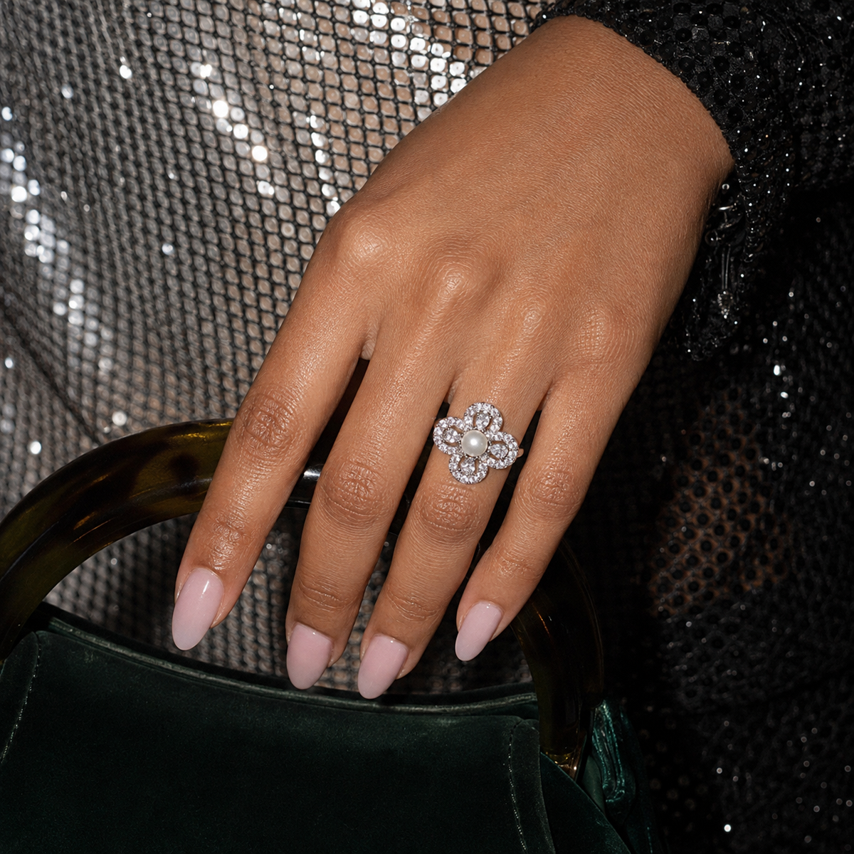 Aurelia Pearl Clover Statement Ring worn with a black embellished outfit and dark green handbag
