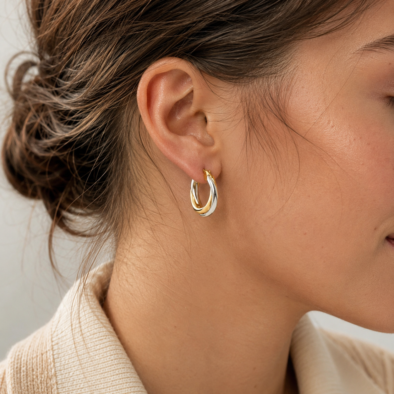 Woman wearing sculpted two-tone hoop earrings in gold and silver, styled for an elegant everyday look
