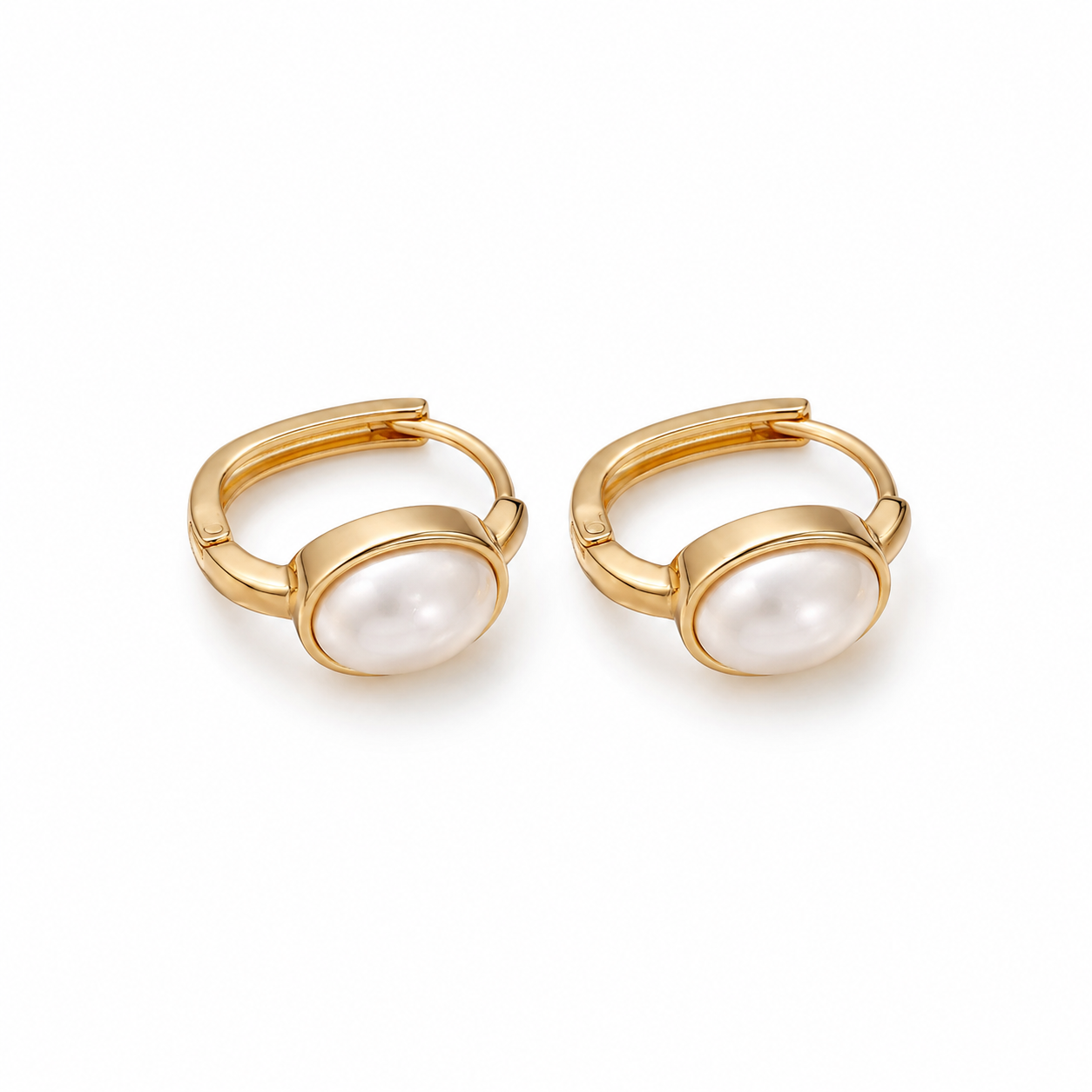 Pair of gold pearl huggie earrings on white background