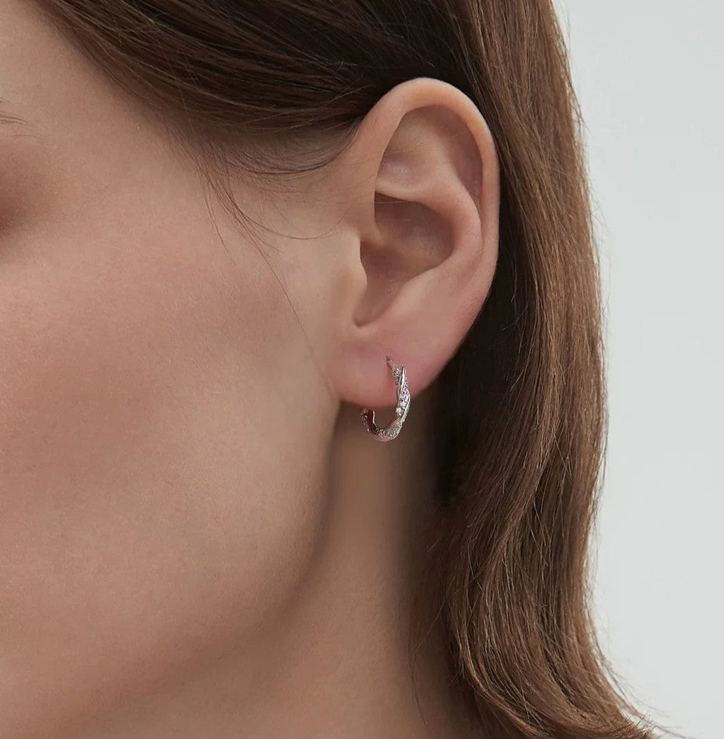 Side angle of model wearing silver twist huggie hoop earrings