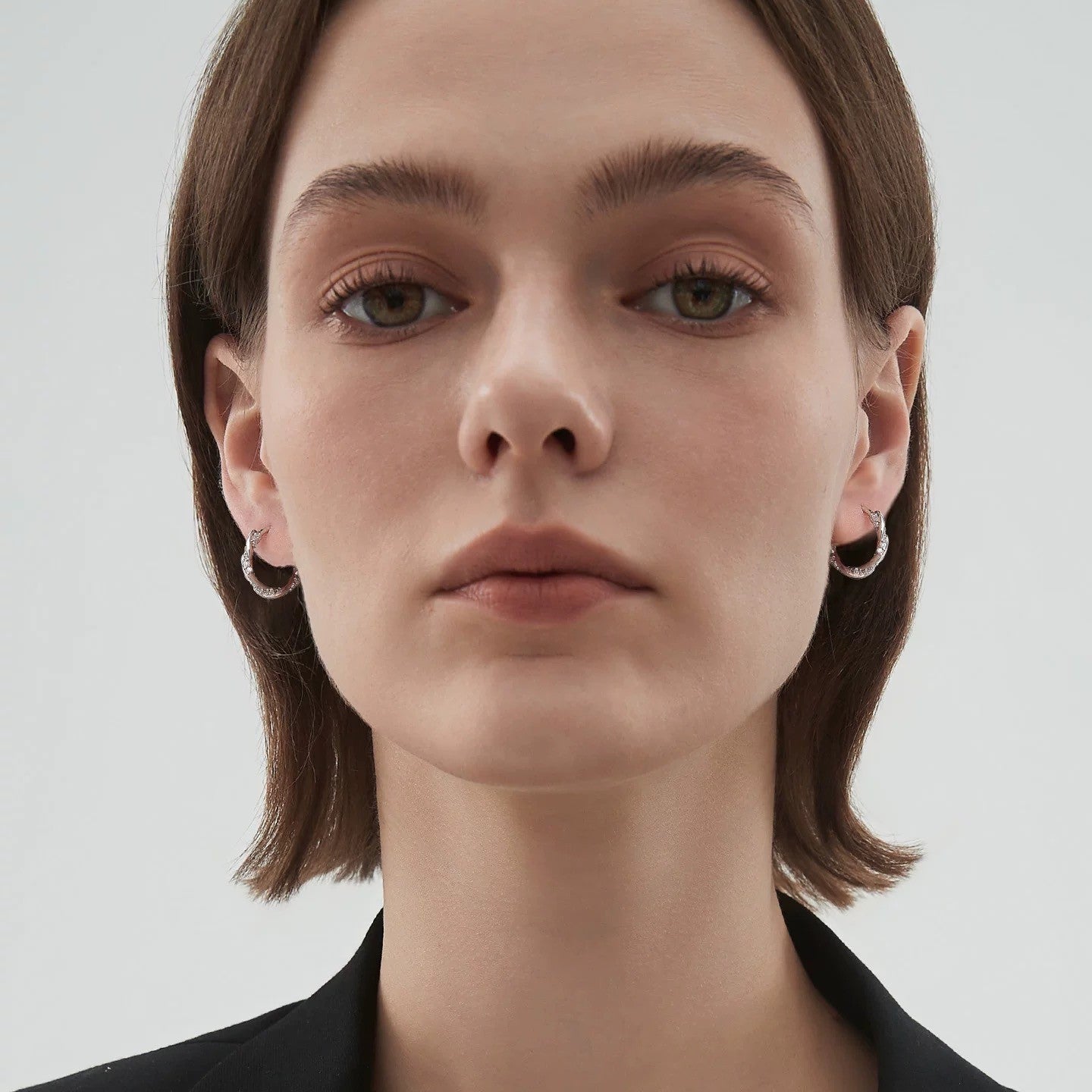 Model wearing silver twist huggie hoop earrings