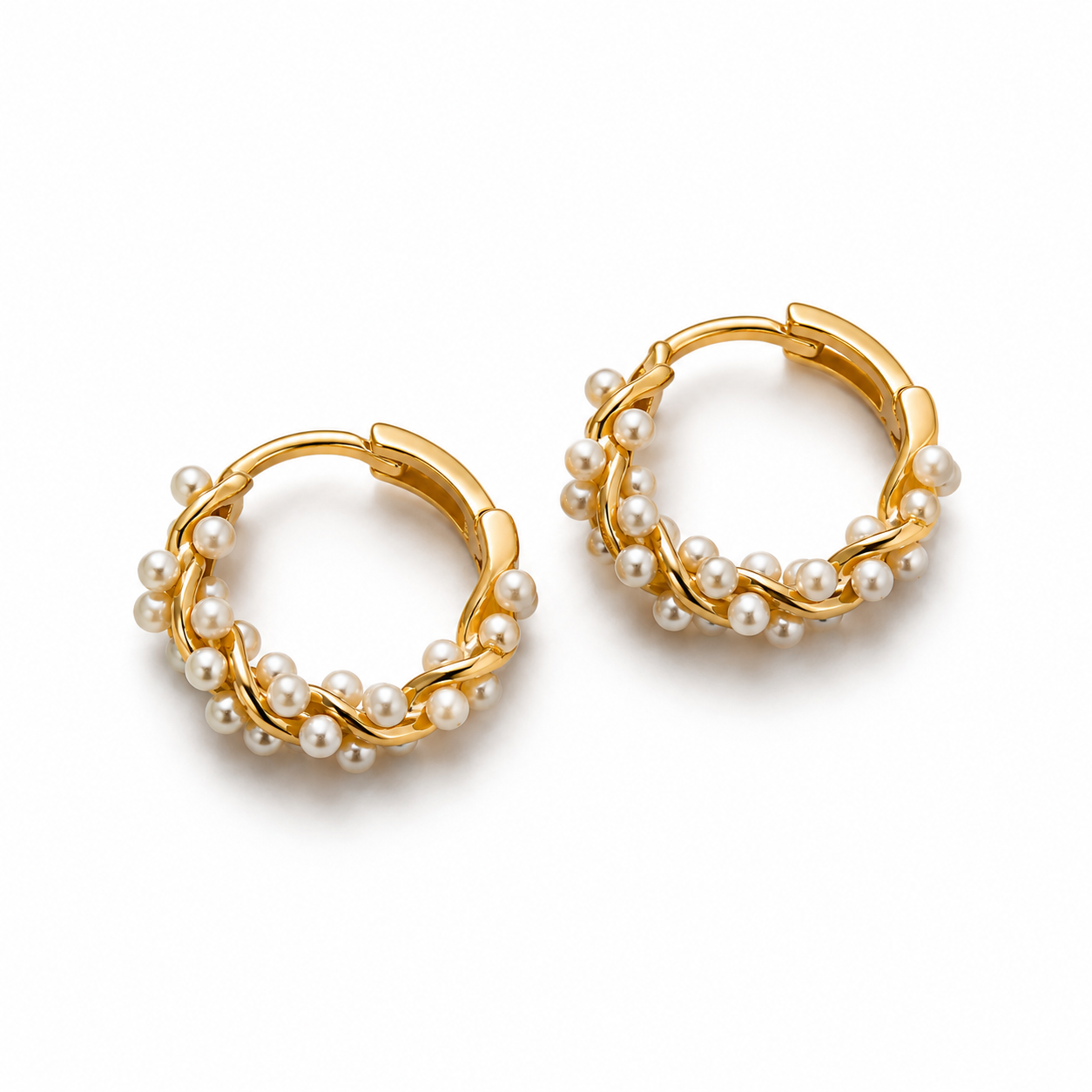 Angled view of gold pearl hoop earrings on white background