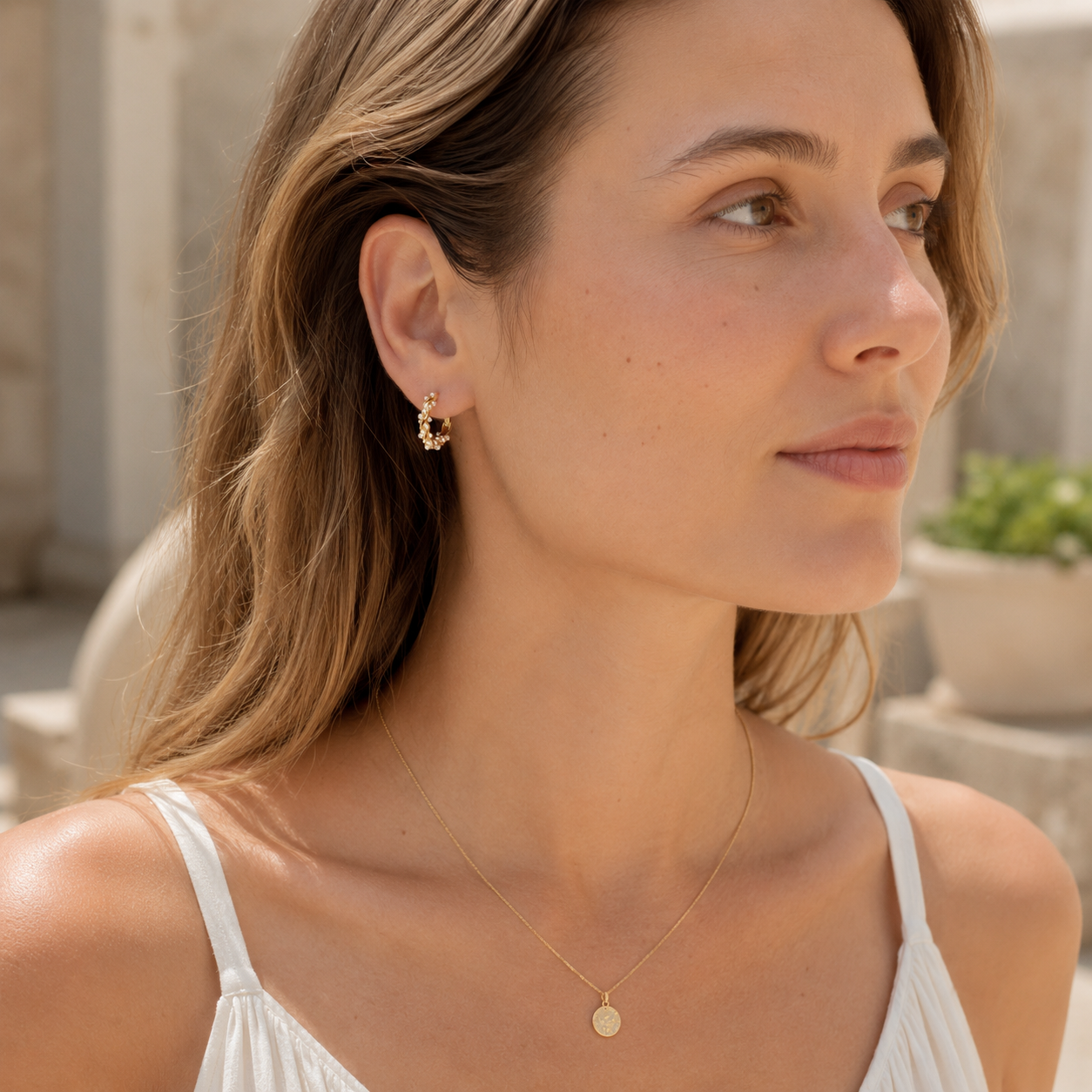 Model wearing gold pearl hoop earrings with a delicate necklace