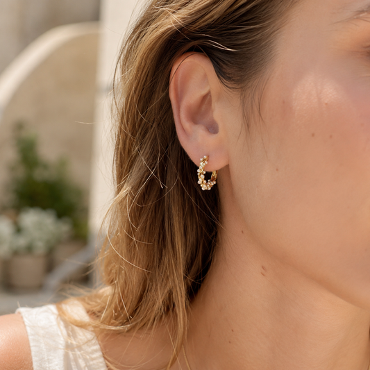 Close-up of model wearing gold pearl hoop earrings