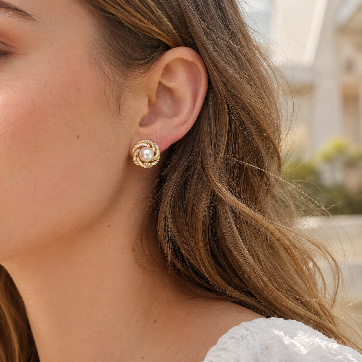 Close-up of model wearing gold pearl stud earrings