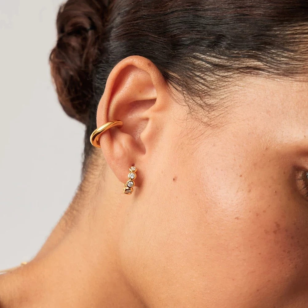 Side view of model wearing gold Elara huggie earrings and a minimalist ear cuff