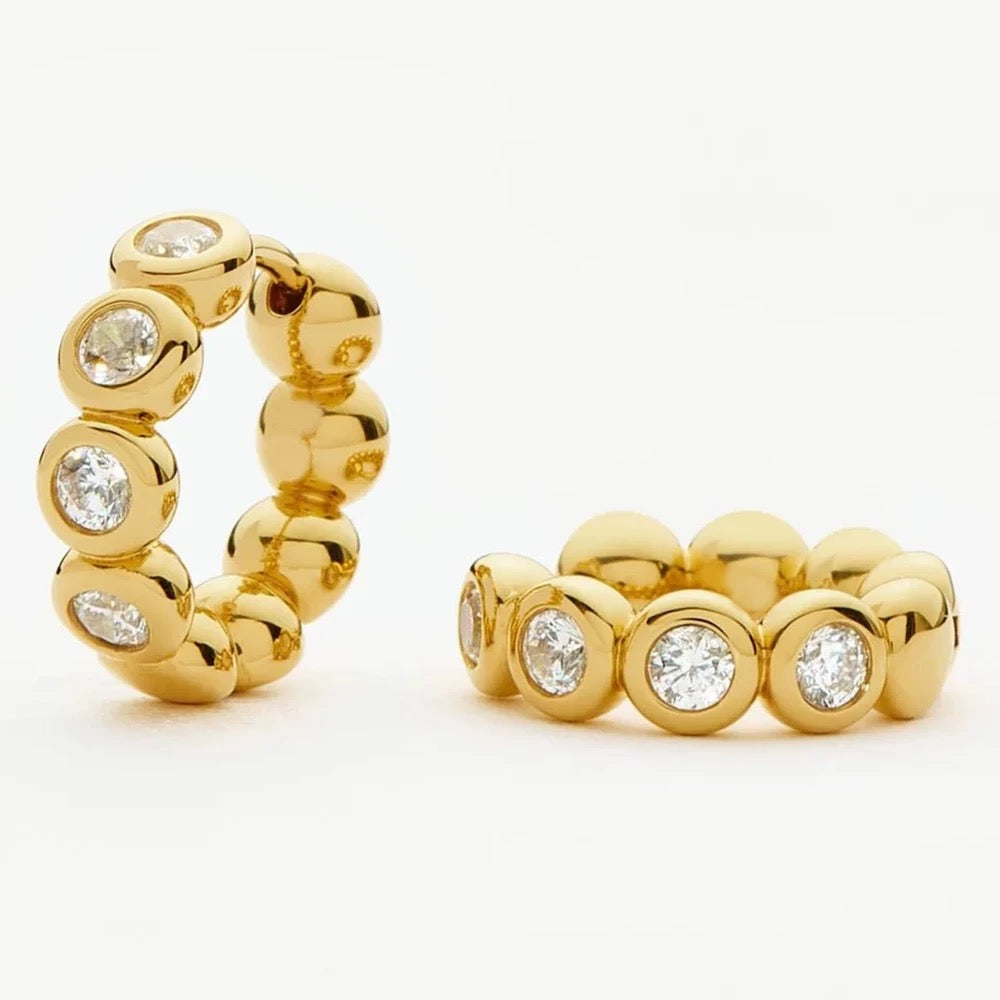 Gold bezel huggie earrings with sculptural rounded links on a white background