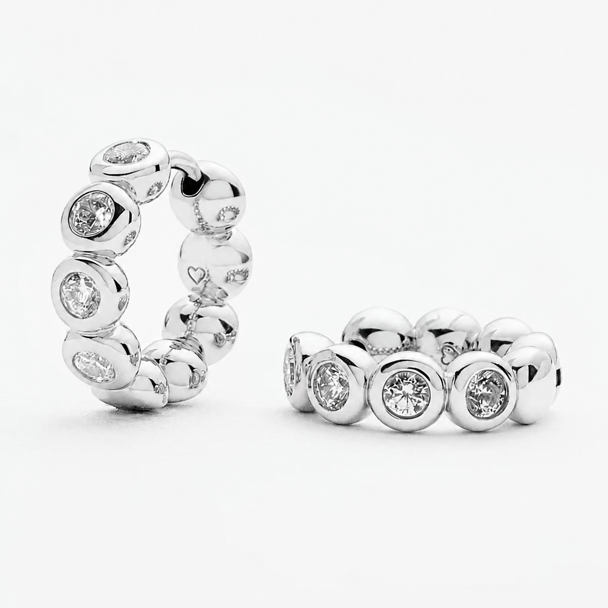 Silver Elara bezel huggie earrings with rounded stone-set details on a white background