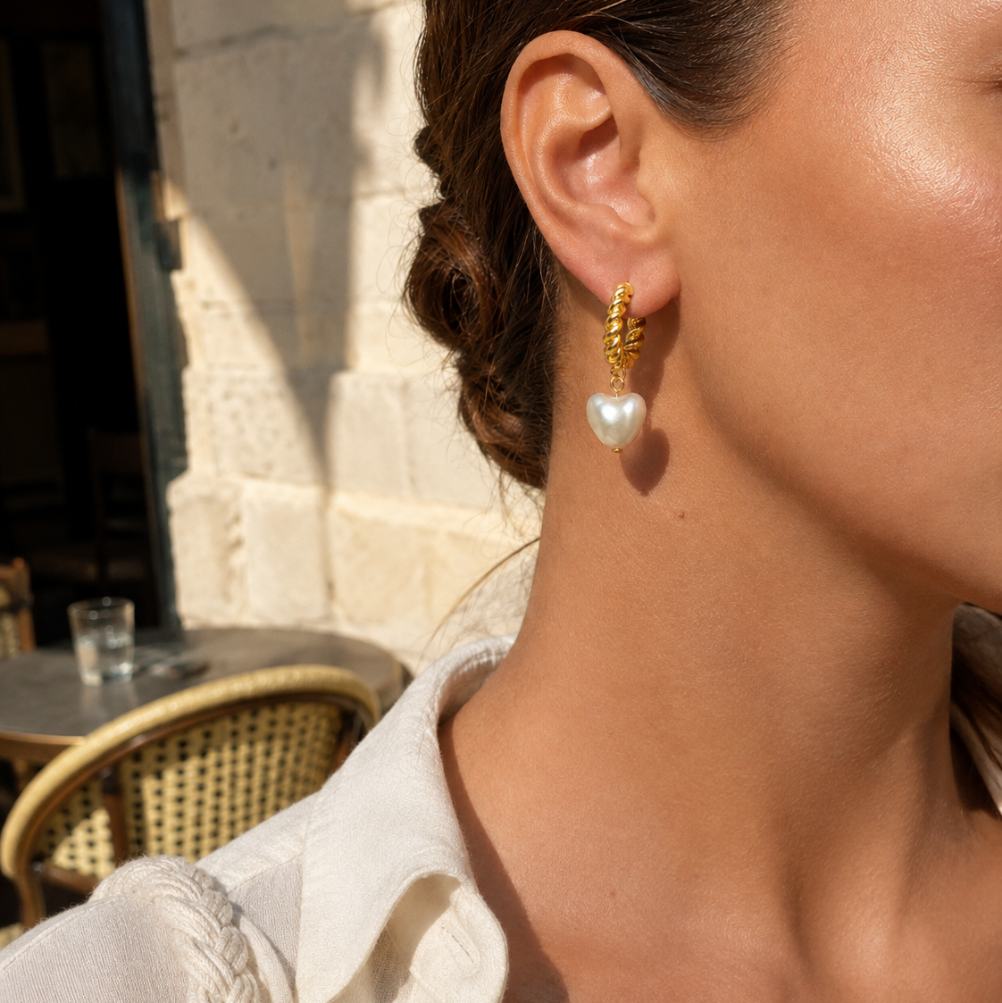 Lifestyle close-up of Amora Pearl Heart Hoop Earrings worn outdoors in warm sunlight
