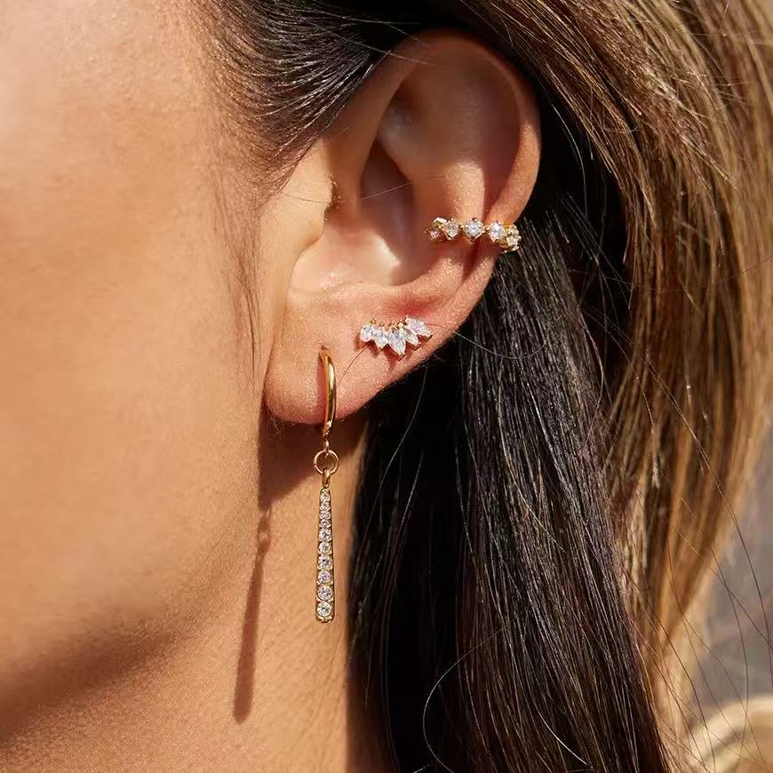 Close-up of gold pavé drop hoop earring styled in a stacked ear look