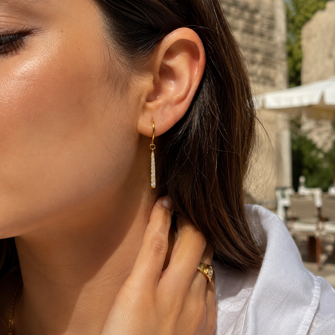 Close-up of model wearing delicate gold hoop earrings with pavé drop detail