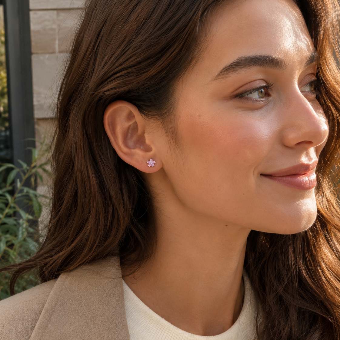 Model wearing delicate pink flower stud earrings with a neutral blazer