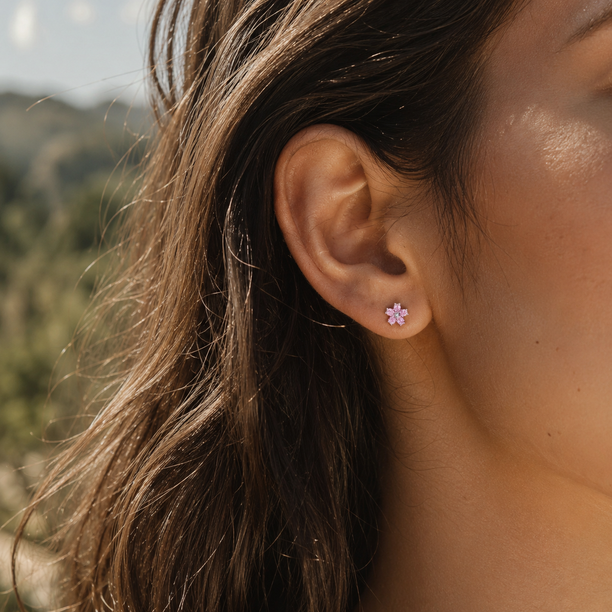 Close-up of Rosalie pink crystal flower stud earring worn outdoors in warm sunlight