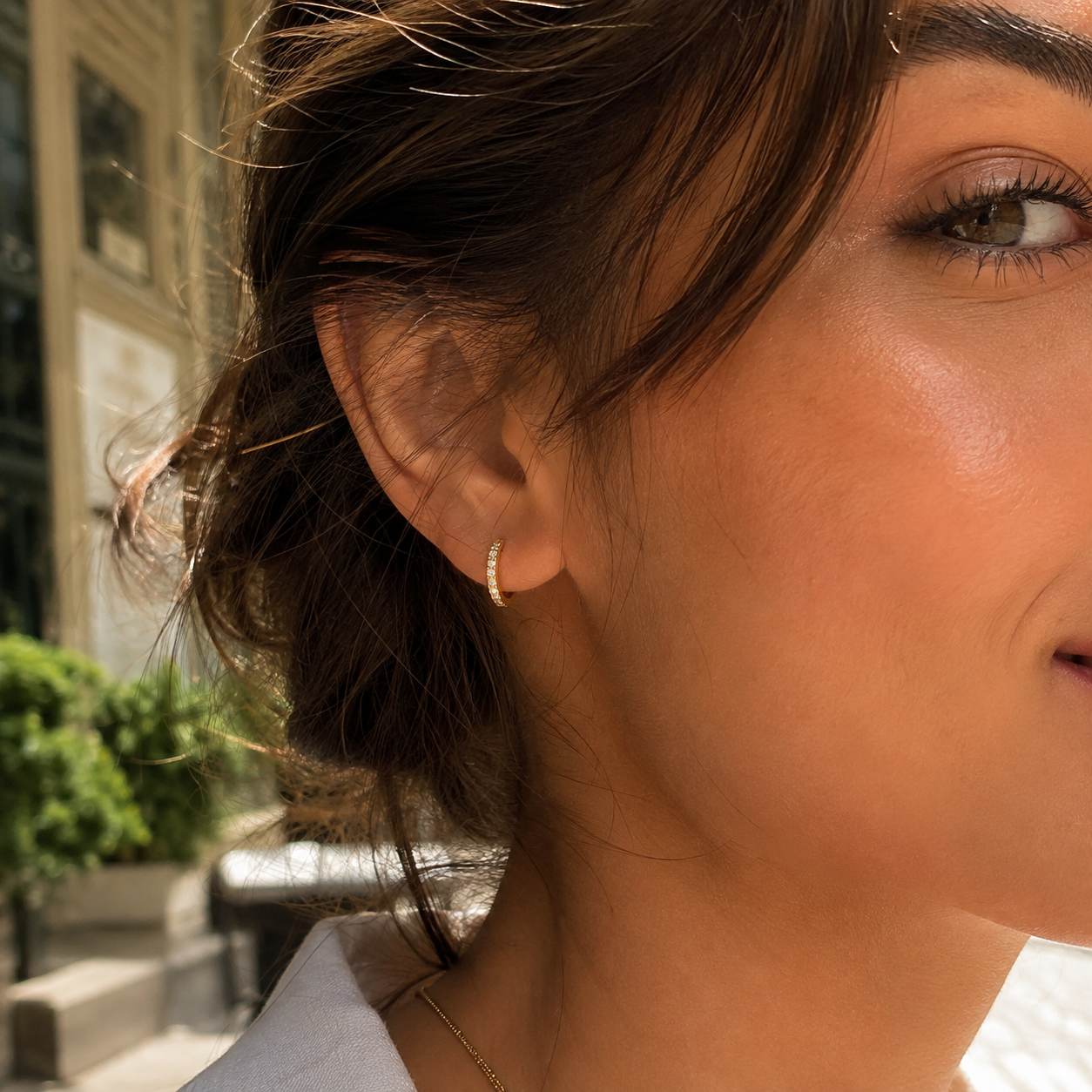 Close-up of gold 8mm pavé huggie earring worn on the earlobe