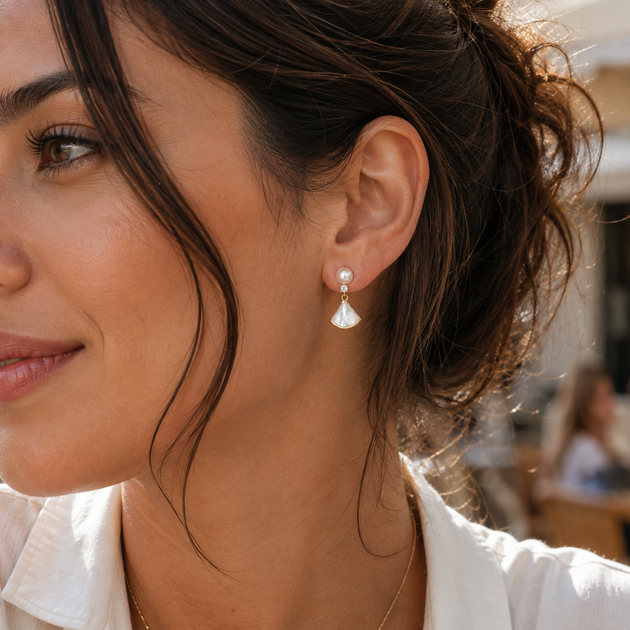 Close-up of Seraphine pearl fan drop earrings worn outdoors in warm sunlight