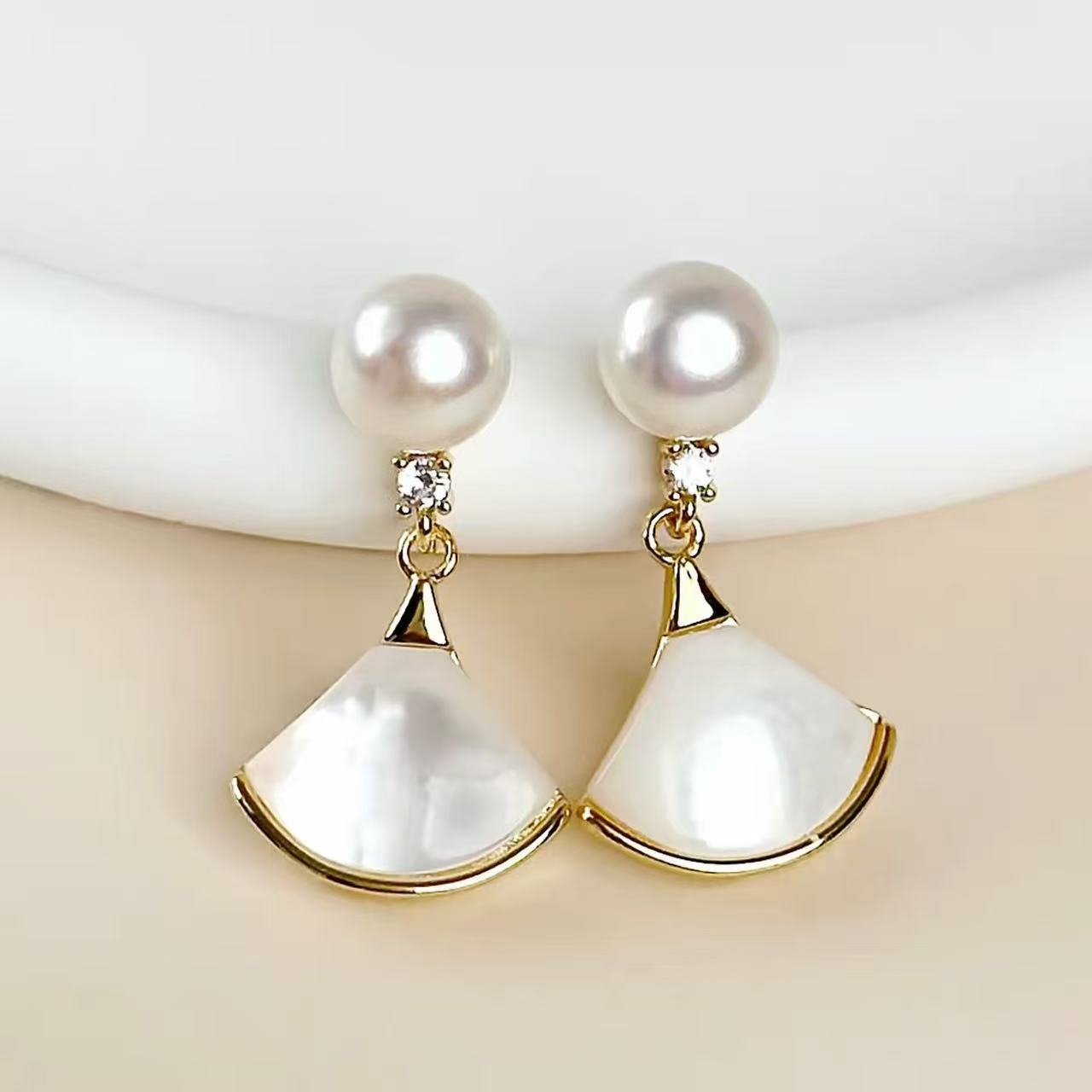Close-up product photo of gold pearl and mother-of-pearl fan earrings