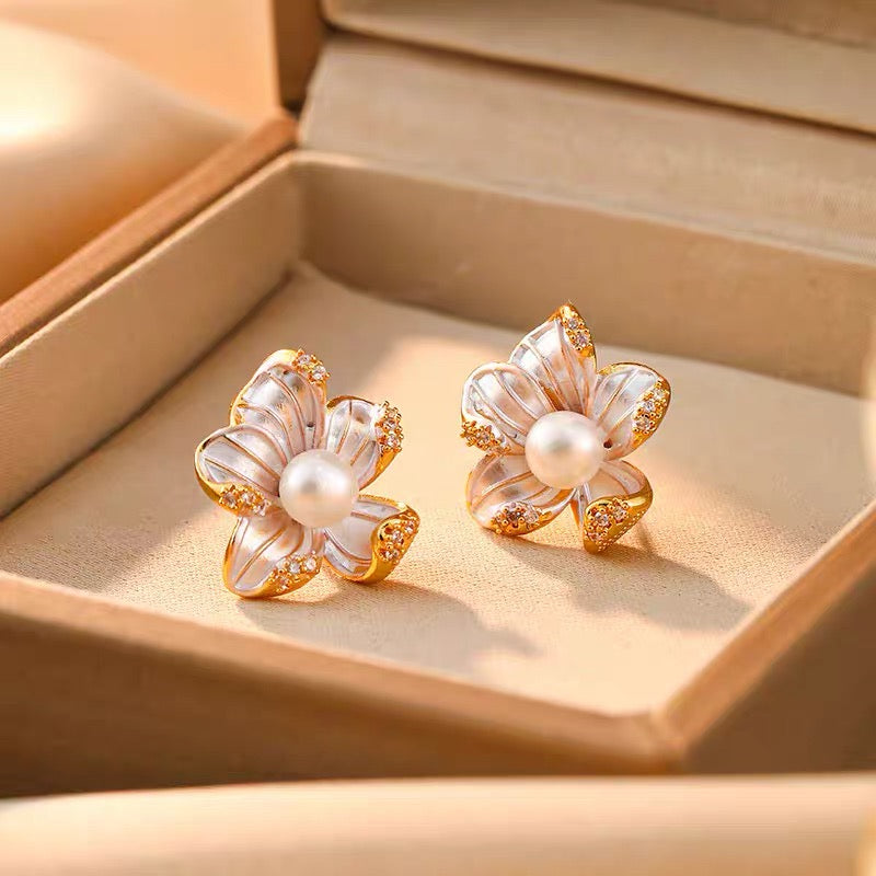 Pair of pearl and mother-of-pearl flower stud earrings displayed in a jewellery box