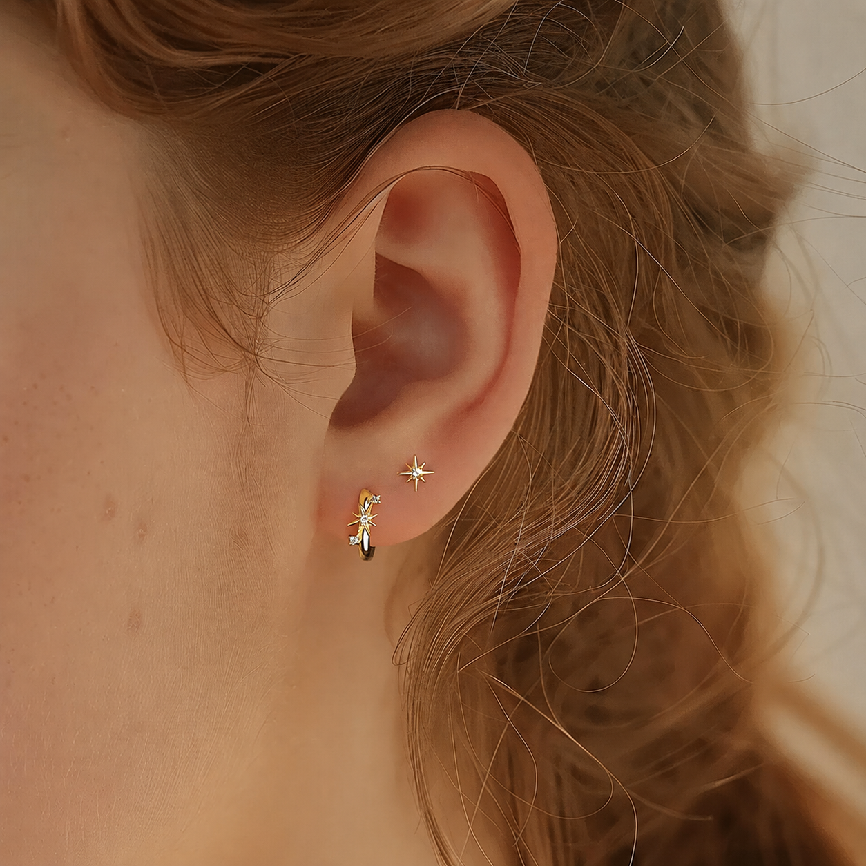 Model wearing starburst stud and huggie earrings