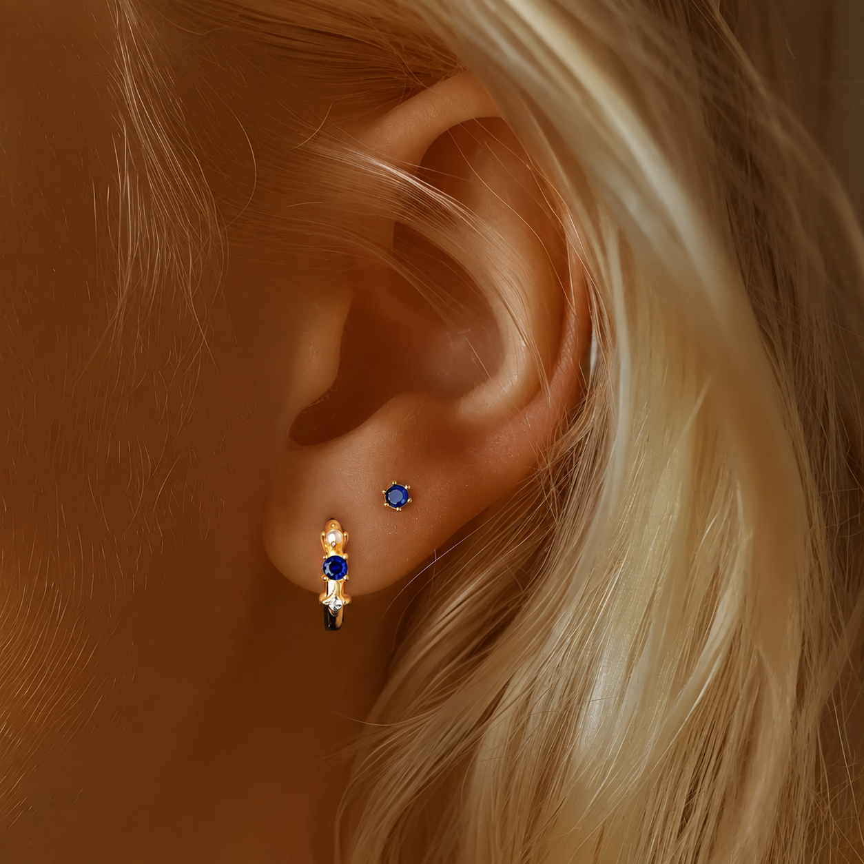 Close-up of model wearing blue cubic zirconia stud and huggie earrings