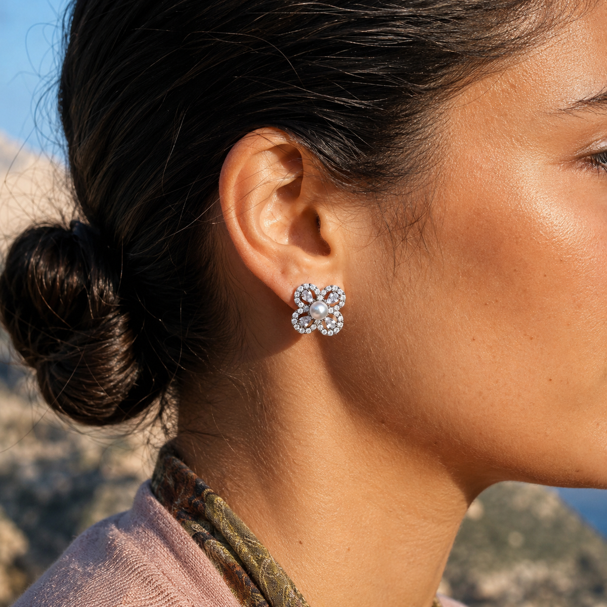 Side-profile close-up of Aurelia Pearl Clover Stud Earrings worn outdoors in bright sunlight