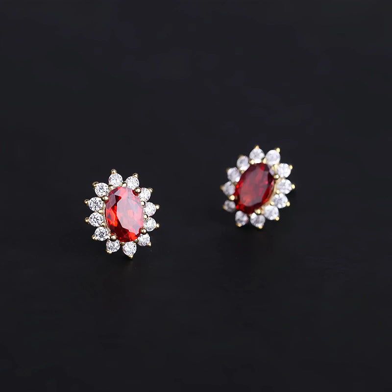 Garnet halo stud earrings worn on ear, featuring oval red garnet framed by sparkling stones