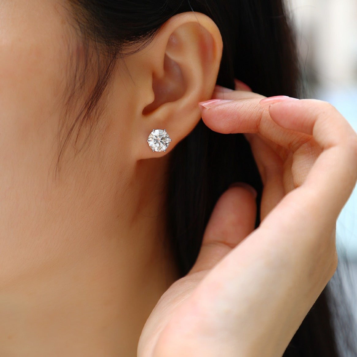Woman wearing round cut cubic diamond stud earrings ¨C elegant silver jewellery by Aeterna Jewellery UK