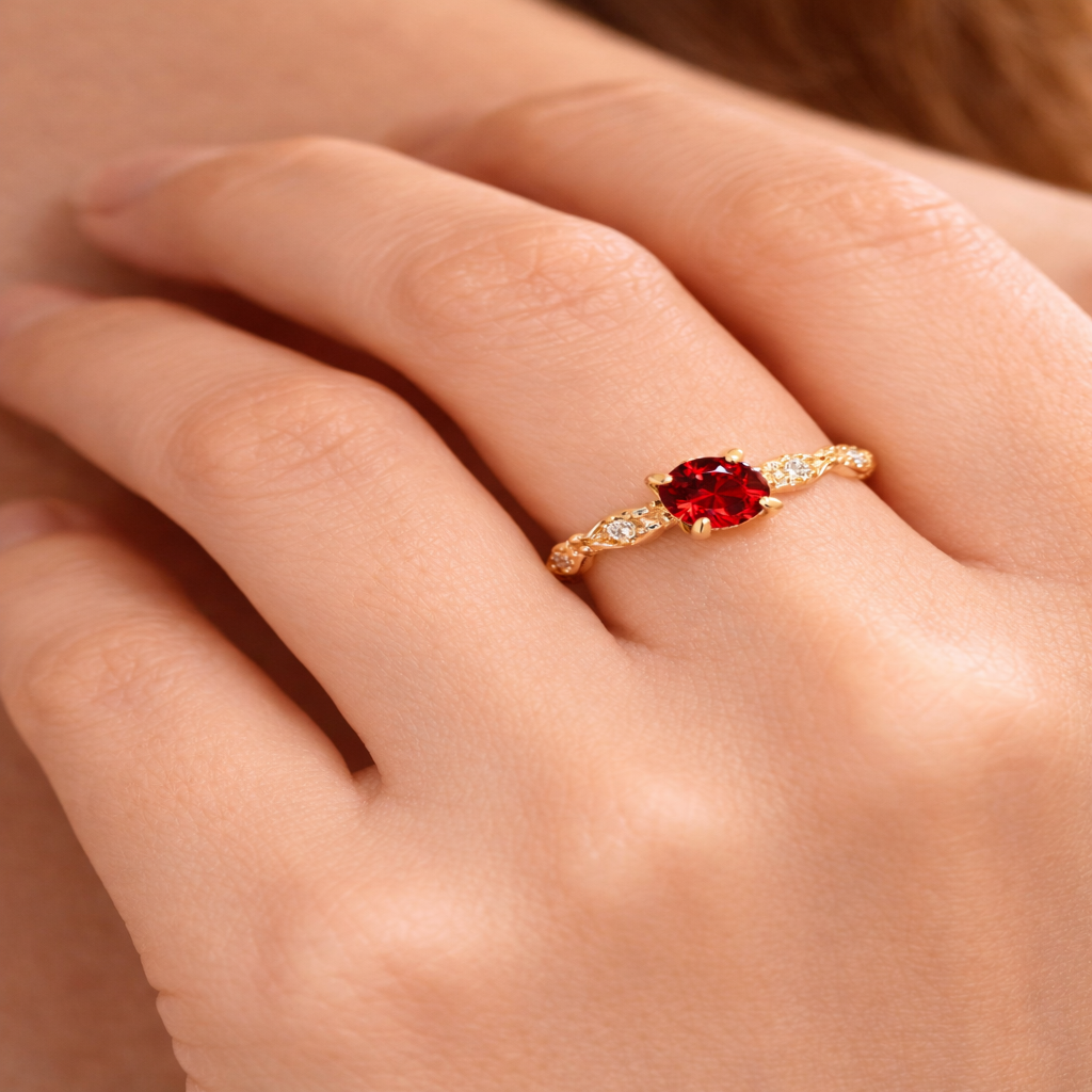 A close-up of a delicate gold-plated sterling silver ring set with a vivid red garnet, worn on a woman¡¯s finger, highlighting its elegant birthstone design and refined details.