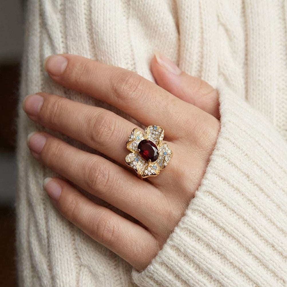 Elegant garnet flower ring in gold with pav¨¦ stones worn on hand in soft indoor daylight