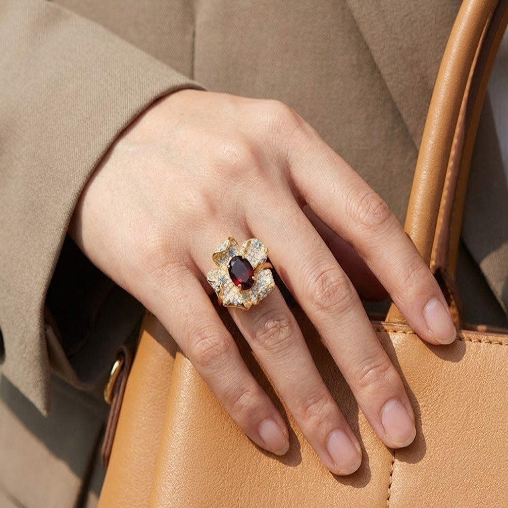 Garnet flower ring in gold with pav¨¦ diamonds worn on hand in a natural outdoor lifestyle setting