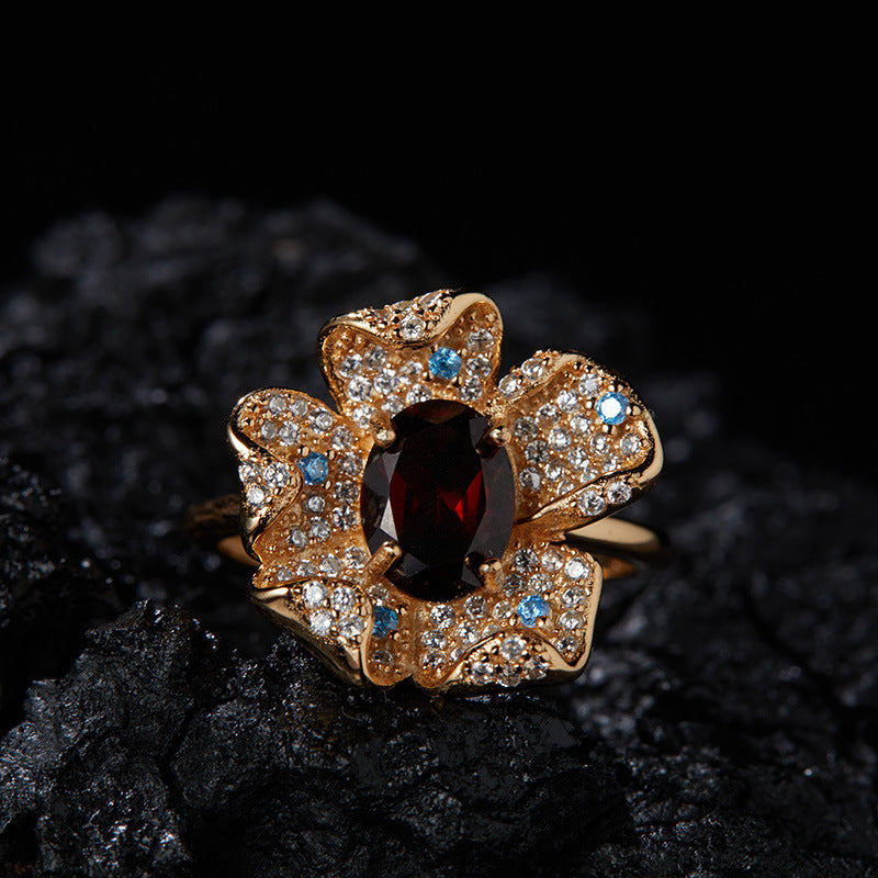 Gold garnet flower ring with pav¨¦ stones photographed on a dramatic dark background