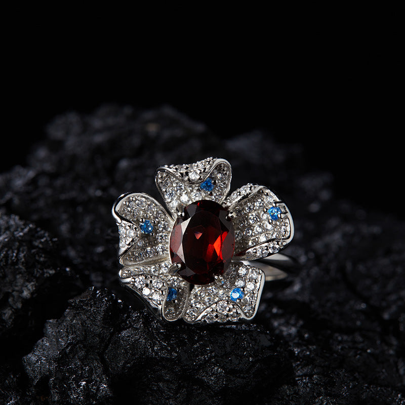 White gold garnet flower ring with pav¨¦ details displayed on a dark textured background