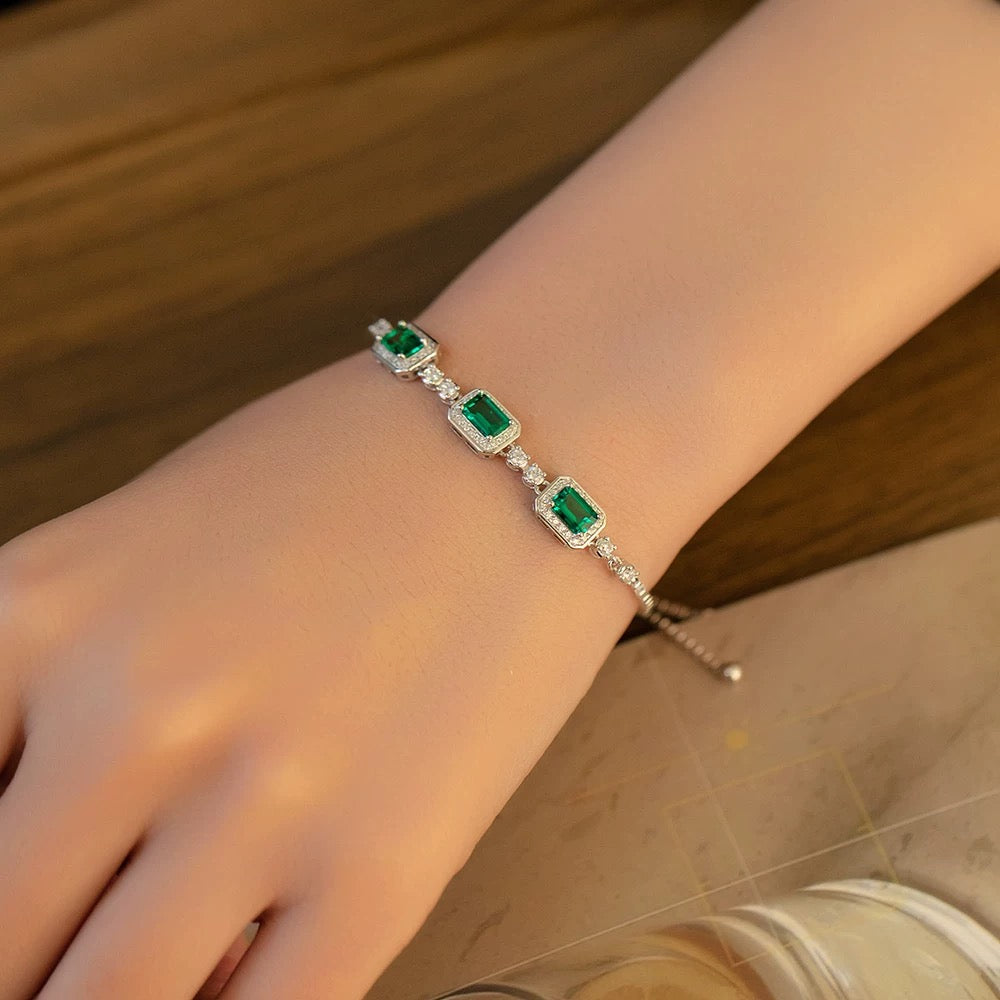 Close-up of emerald trio bracelet on wrist, reflecting bright green brilliance