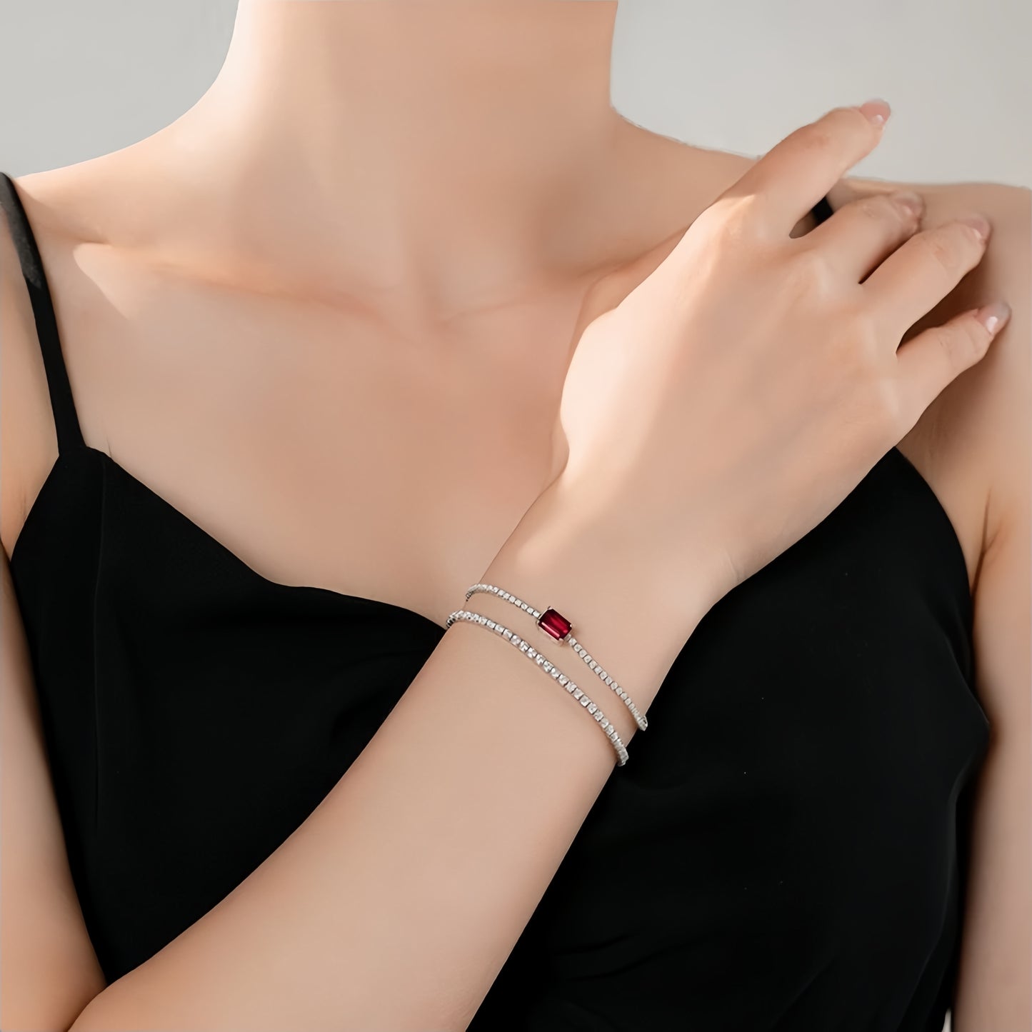 Model wearing ruby solitaire bracelet by Aeterna Jewelry with elegant black dress