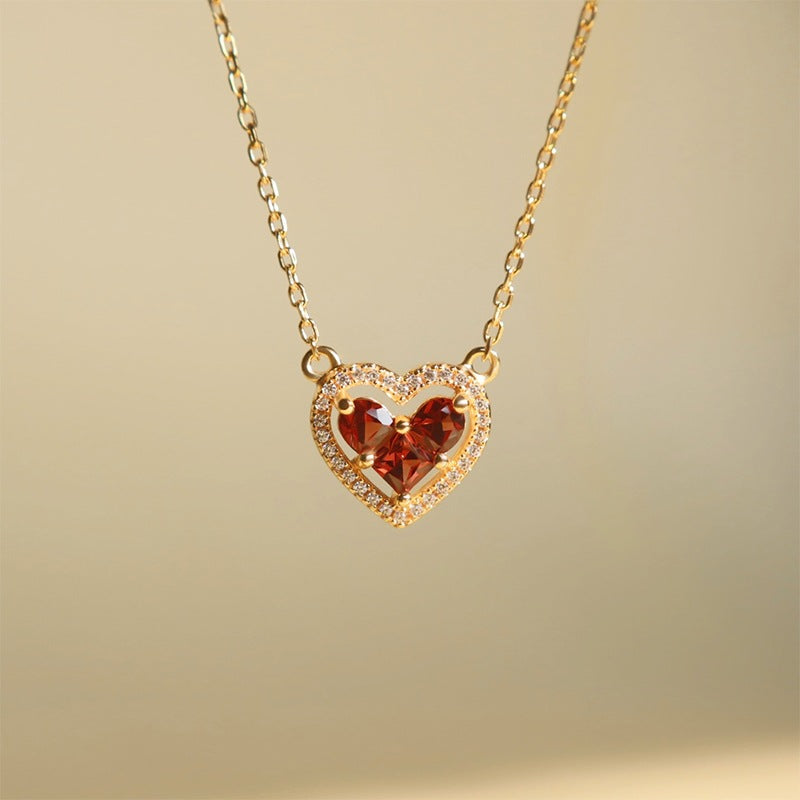 Gold heart garnet necklace with diamond accents in soft lifestyle lighting