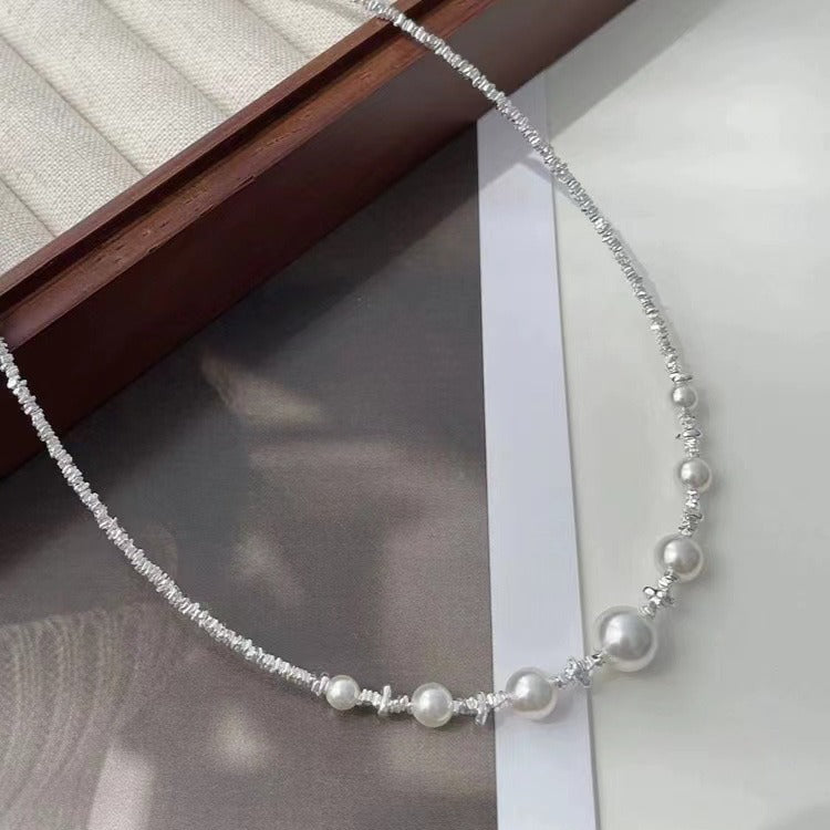 Close-up of Aeterna Jewelry asymmetric freshwater pearl necklace with hammered silver beads, elegant natural light composition