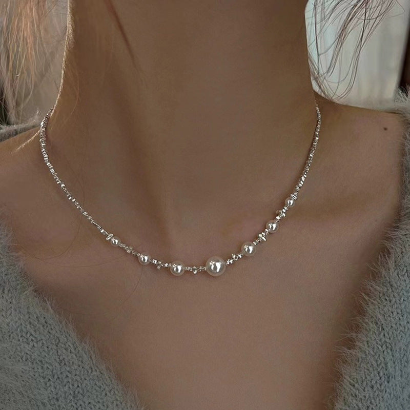 Model wearing Aeterna Jewelry asymmetric freshwater pearl and silver necklace, minimalist neckline view with soft natural light