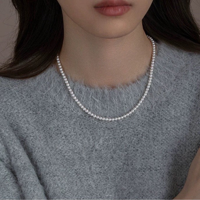 Model wearing Aeterna Jewelry classic freshwater pearl necklace, simple and elegant styling with soft knit sweater