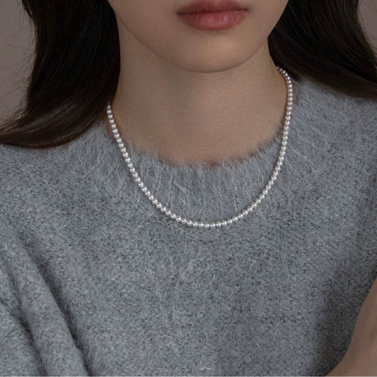 Model wearing Aeterna Jewelry classic freshwater pearl necklace, simple and elegant styling with soft knit sweater
