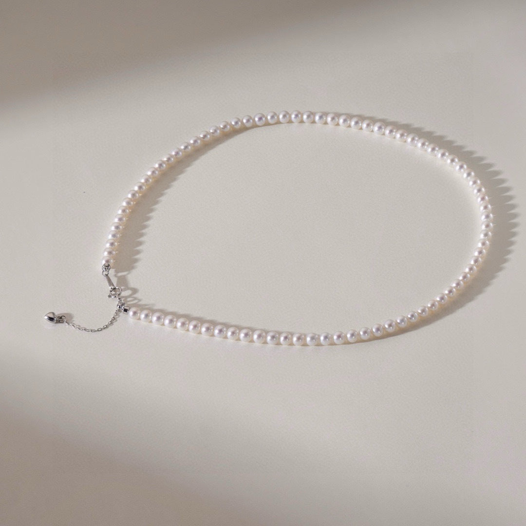 Classic freshwater pearl necklace with sterling silver clasp by Aeterna Jewelry, minimal design with soft lighting and elegant shadows